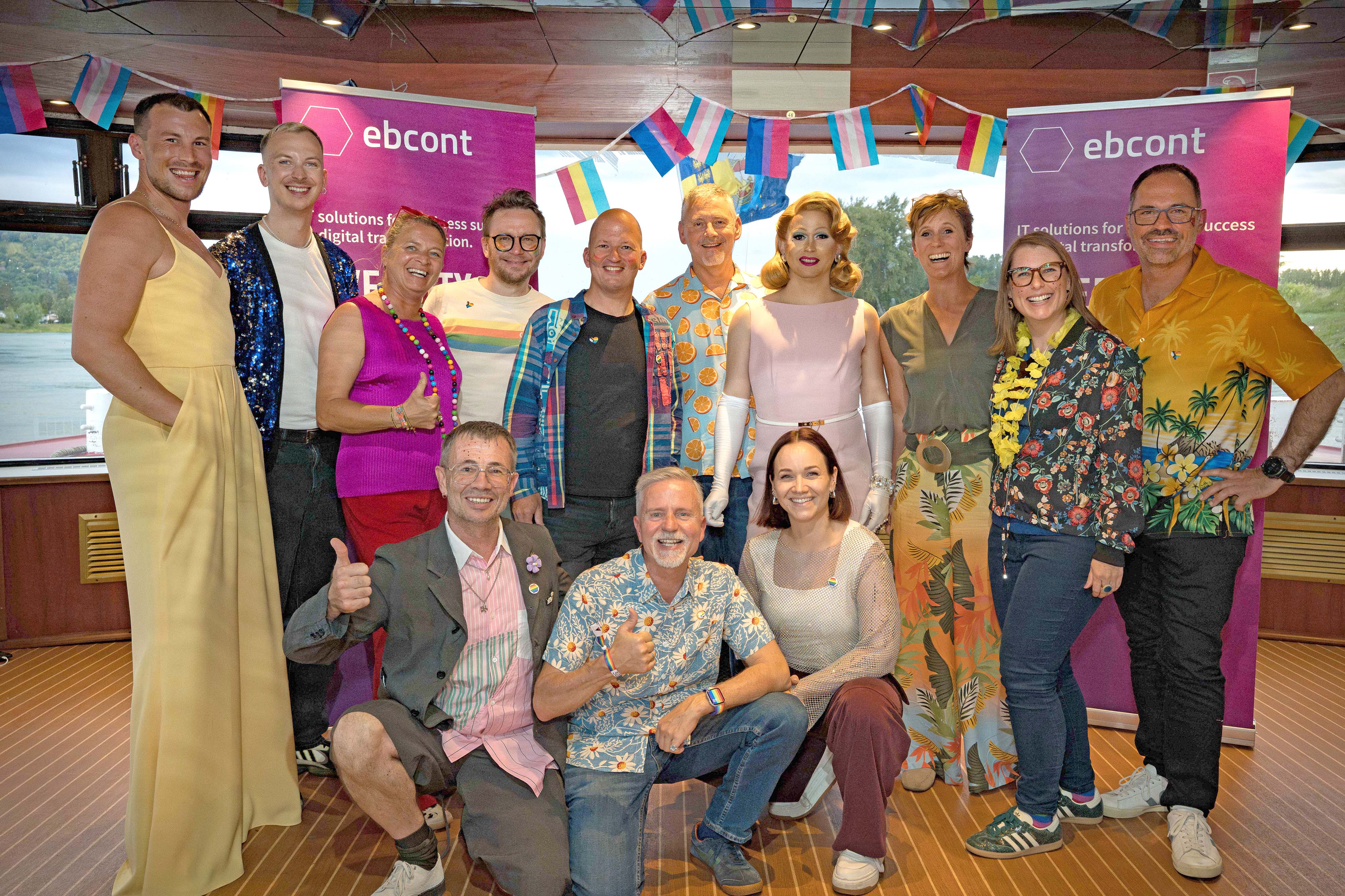 Many people dressed in colorful clothing are standing together, smiling and laughing at the camera.
